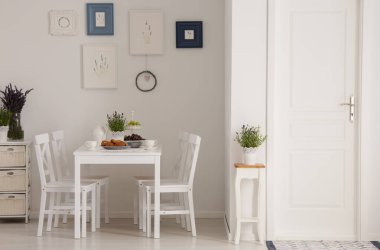 Beyaz koltukları ve bitkiler, posterler ve kapı ile en az yemek odası iç tablo. Gerçek fotoğraf