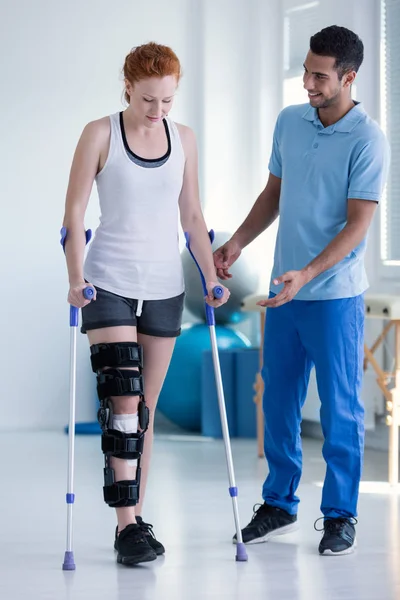 Fizjoterapeuta Pomaga Kobieta Usztywniacz Nodze Chodzenie Kulami — Zdjęcie stockowe