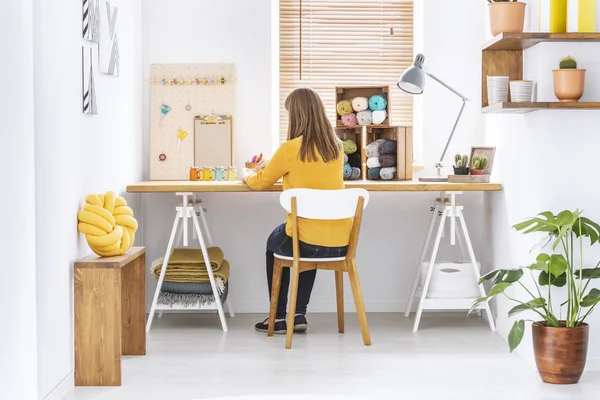 妇女坐在办公桌在家庭办公室内部与针织羊毛 组织者和黄色枕头 — 图库照片