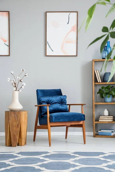 花在木桌旁边的蓝色扶手椅在灰色客厅内部与海报 真实照片 — 图库照片