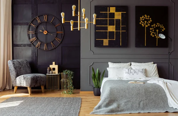 深灰色卧室内饰的真实照片墙壁上的造型和绘画 双人床与枕头 金灯和花卉扶手椅 — 图库照片