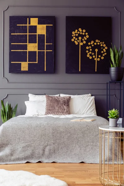 灰色墙上的黑色和金色海报 卧室内有枕头和植物 真实照片 — 图库照片