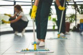 Detail na čištění specialista s žluté rukavice drží mop při stírání podlahy