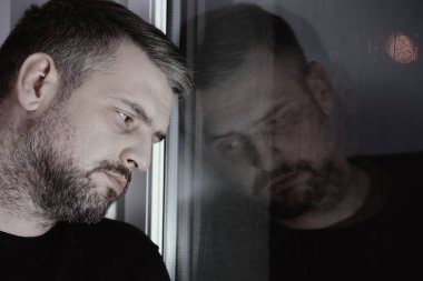 Sinir krizi ve ruhsal bozukluk pencereden bakarak üzgün adam