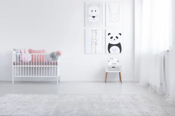 粉红色枕头在摇篮和海报墙上的白色儿童的房间内地毯 真实照片 — 图库照片