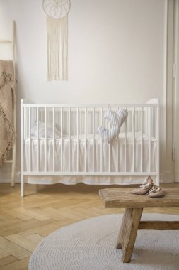 Ahşap dışkı parlak bebeğin yatak odası iç beyaz beşik ile yuvarlak halı üzerinde ayakkabı ile. Gerçek fotoğraf