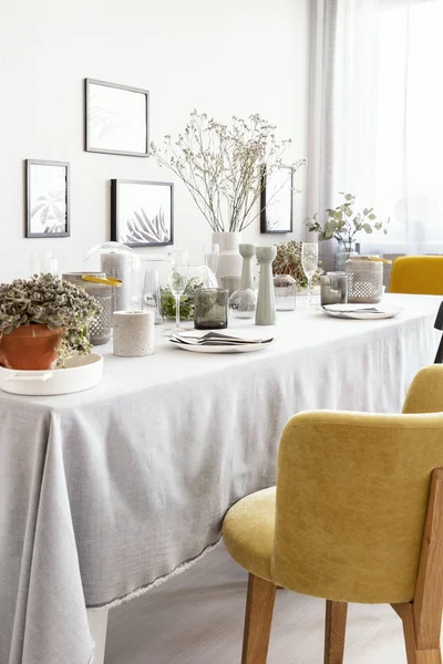 明るいダイニング ルーム インテリア花とポスターの食器とテーブルで黄色の椅子 実際の写真 — ストック写真