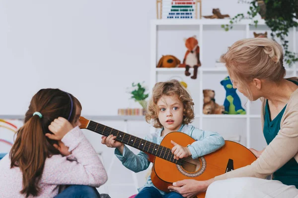 Ładny Mały Chłopiec Uczy Się Grać Gitarze Podczas Lekcji Przedszkola — Zdjęcie stockowe