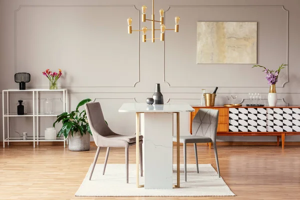 Industrial style, golden pendant light above an exceptional marble table in a trendy dining room interior with eclectic decor
