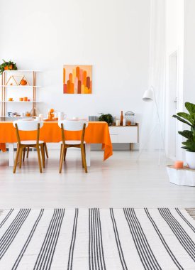 Dikey görünüm uzun masa, sandalye ve turuncu ayrıntıları ile oturma odası. Gerçek fotoğraf kavramı