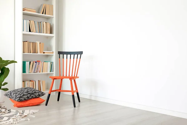 空の壁にコピー スペースを持つ白い部屋のインテリアにオレンジと黒の椅子の隣に枕 実際の写真 — ストック写真