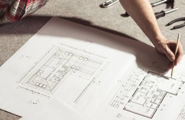 Adam bir marangozluk dükkanında bir bina planı çizim