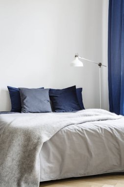 Karanlık yastıkları ile rahat ve en az çift kişilik yatak ve bir battaniye tarafından beyaz, boş bir parlak yatak odası iç duvar