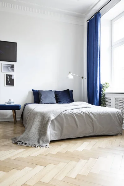 ネイビー ブルーのテキスタイルとヘリンボーンのフローリングの明るい寝室のインテリアのコーナーで居心地の良いダブルベッドのローアングル ビュー — ストック写真