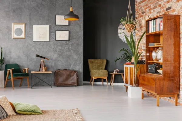 Flat interior with texture, black and brick walls in real photo with retro cupboards, fresh plants, posters, briefcase and telescope on end table