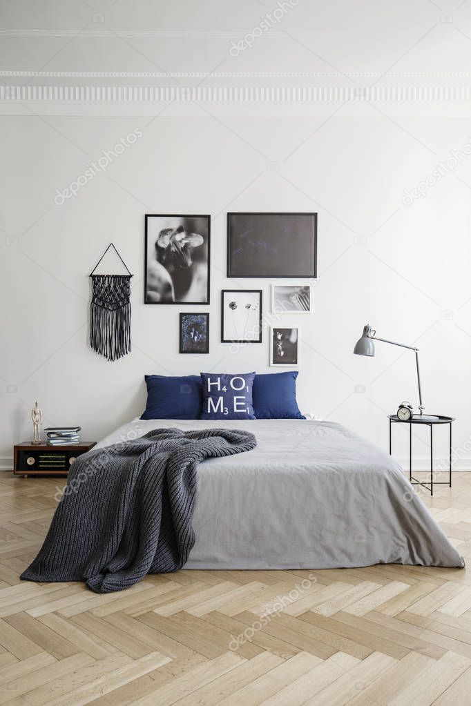 Blue and grey bedroom with gallery of posters in stylish interior. Real photo concept