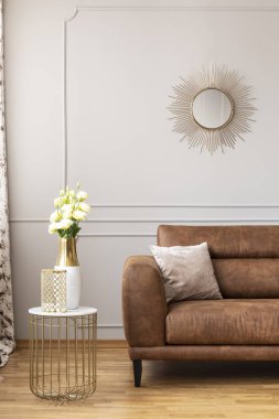 Kahverengi deri kanepe zarif ev ışık oturma odasında yanında şık masada bir vazoda beyaz güller