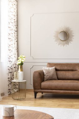 Yanında rahat deri üzerine çiçekli vazo ile şık tablo kanepe lüks oturma odası iç, gerçek fotoğraf bej yastık ile