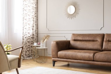 Altın ayna ile kalıplama ile masa ve koltuk düz iç deri kanepe üstünde gri duvar. Gerçek fotoğraf