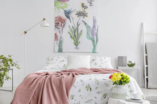 粉色毯子扔在国王大小的床与花卉床上用品在真实照片的白色卧室内饰与墙壁上的绘画 — 图库照片