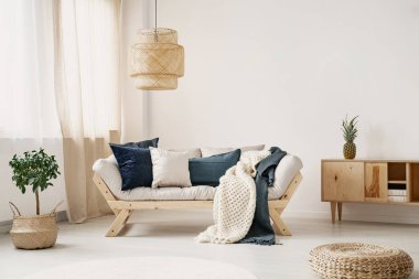 Yastıklar ve gerçek fotoğrafta beyaz oturma odası iç pencere perdeleri, saman lamba ve katta taze bitki ile yerleştirilen iki battaniye ile hafif lounge