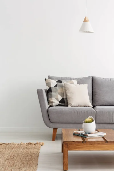 パターン化された枕と敷物の自然素材で作られたソファのエレガントなアパートメント グレーと雑誌とコーヒー テーブルのリビング ルームの垂直方向のビュー — ストック写真