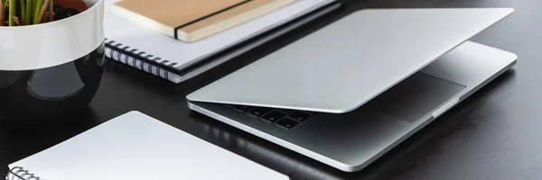 真正的照片与特写的银色笔记本电脑放在黑色办公桌与笔记本电脑 — 图库照片