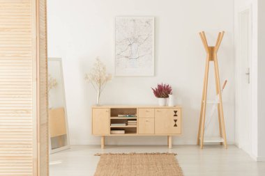 Çiçekler beyaz giriş salonu iç posteri ile rafa yanındaki ahşap dolap üzerinde. Gerçek fotoğraf