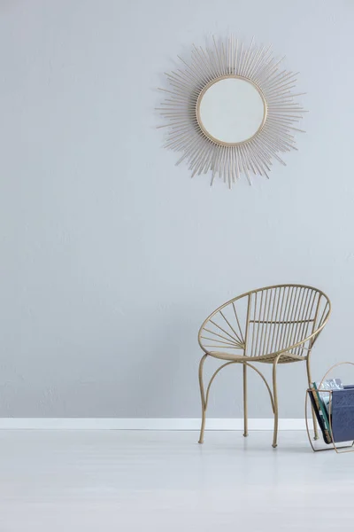 コピー スペースとシンプルなホールのインテリアの肘掛け椅子の上の灰色の空の壁にゴールドのミラー 実際の写真 — ストック写真