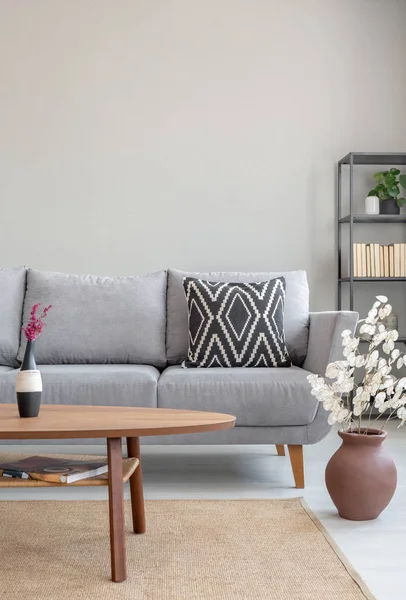 Holztisch Vor Grauem Sofa Schlichtem Wohnungsinterieur Mit Blumen Und Teppich — Stockfoto