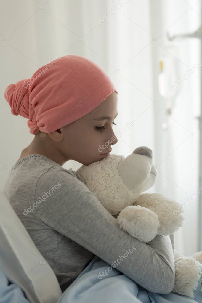 Vertical view of sick teenager girl in hospital bed after chemotherapy