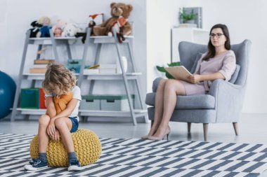 İçine kapanık bir çocuk üzerinde bir kabarık bir ofiste profesyonel bir terapist ile bir değerlendirme oturumu sırasında oturan bir otizm spektrum bozukluğu ile.