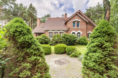 Herdem yeşil ile yeşil arka bahçe ve bir Arnavut kaldırımlı relax yer. Arka planda bir kırmızı tuğla konak.