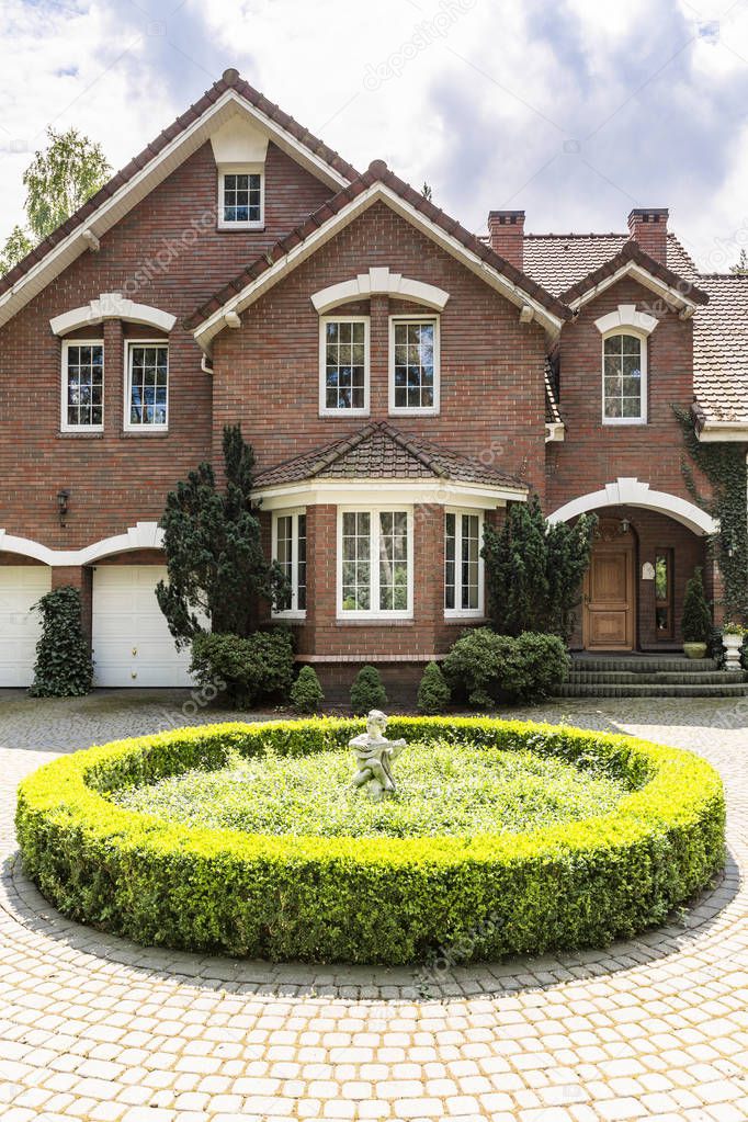 Round garden in front of house in english style with windows and plants