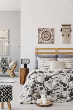 Desenli dışkı ve lamba SCANDI yatak odası iç posteri ile yastıkları yatakta yanında. Gerçek fotoğraf