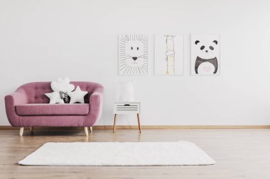 Pembe kanepeyle şık ferah bebek odası iç duvarda hayvanlar posterler ile şirin yastıklar