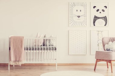 Parlak bebek odası ile şirin yastıklar ve pembe battaniye, hayvan çizimleri rahat koltuk yanındaki duvarda beyaz çocuk odası