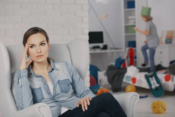 Worried Mother Relaxing Armchair While Son Adhd Making Mess — Stock Photo, Image