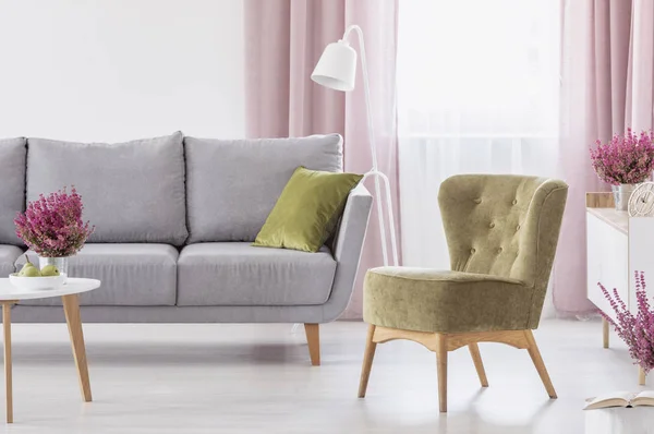 绿色扶手椅站在白色客厅内部与灰色的沙发 窗口与柔和的粉红色窗帘和新鲜的石南花在真实的照片 — 图库照片