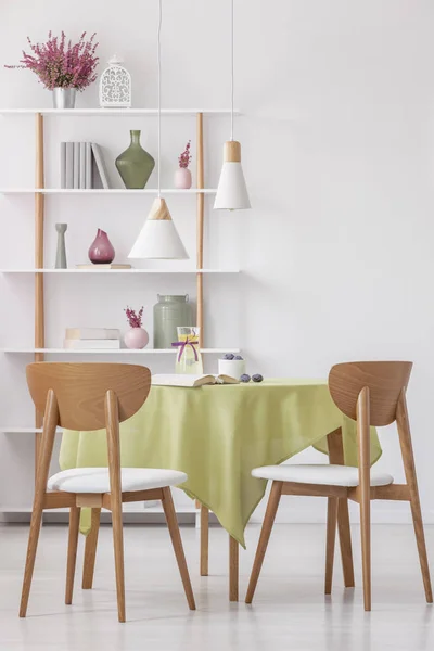 木制椅子的垂直视图在圆形桌与橄榄绿色桌布在明亮优雅的客厅 真实的照片 — 图库照片
