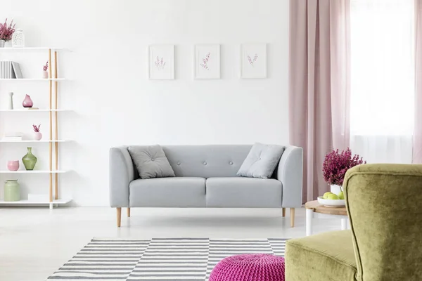 灰色休息室与枕头放置在真实照片的白色客厅内部与海报墙上 肮脏的粉红色窗帘在窗口 机架与装饰和书籍和石南花 — 图库照片