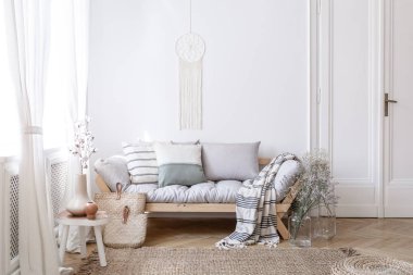 El yapımı dreamcatcher makrome beyaz bir duvar ile bir parlak ve doğal oturma odası iç çiçeklerle cam vazolar