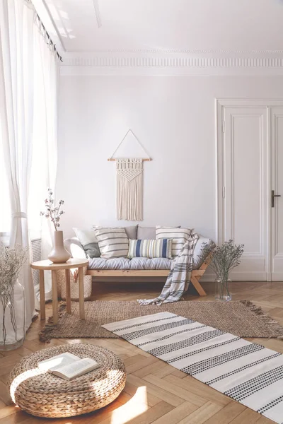 在柳条奥斯曼和人字形地板的米色起居室内有木制沙发和靠垫的阳光 — 图库照片