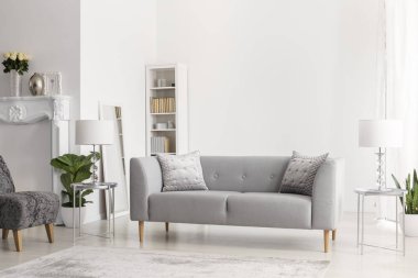 Gri kanepe ve lambaları beyaz daire iç çiçek ve koltuk ile gümüş tablolarda. Gerçek fotoğraf