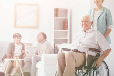 Gülümseyen kıdemli tekerlekli sandalye ile huzurevinde gönüllü olarak felç