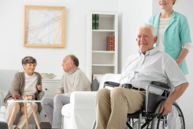 Mavi üniformalı Engelli yaşlı adam tekerlekli sandalye hemşirelik evde destek dostu hemşire