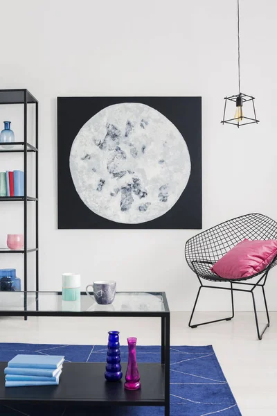Vertical view of moon graphic on the wall of stylish white living room interior th trendy armchair, real photo