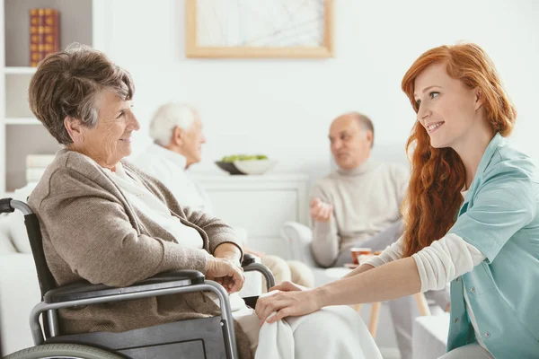 红发微笑的护士帮助临终关怀的老年患者 — 图库照片