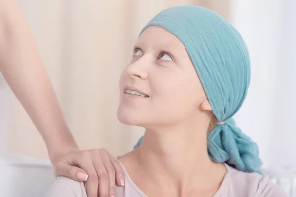 Woman with cancer wearing headscarf looking up at someone