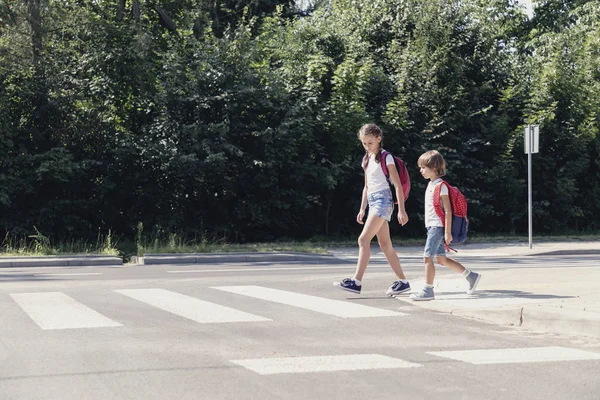 Κορίτσι Και Αγόρι Σακίδια Περπατώντας Στη Διάβαση Πεζών Από Σχολείο — Φωτογραφία Αρχείου